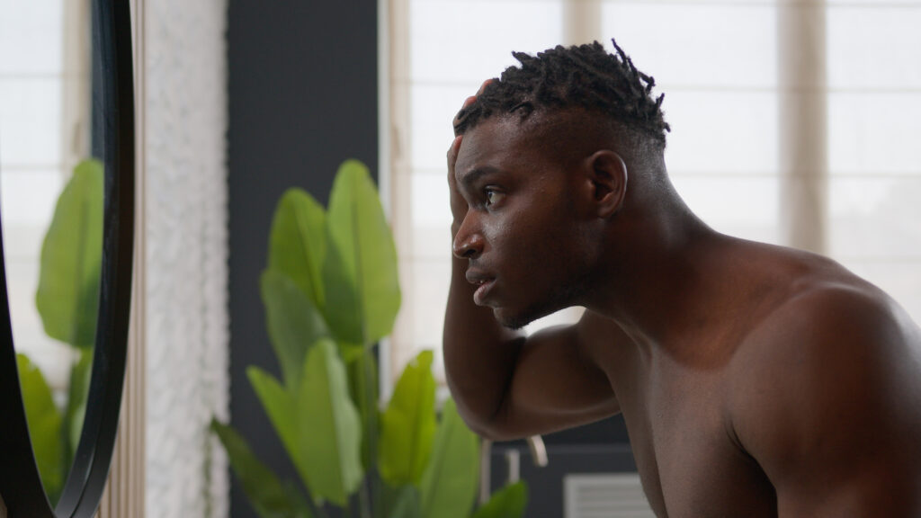 Man inspects hairline in mirror